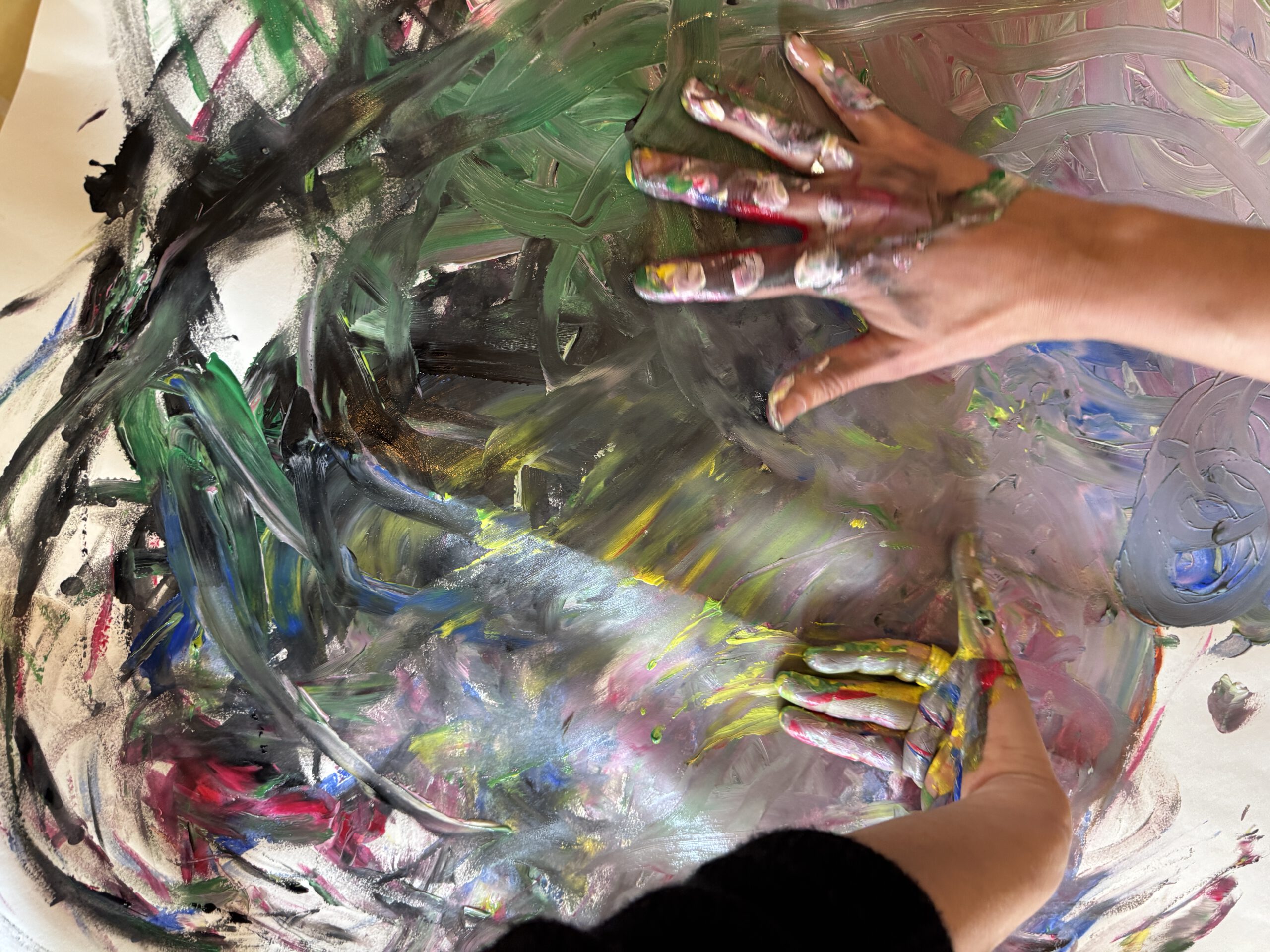Hände arbeiten mit Farbe auf einem großformatigen Bild